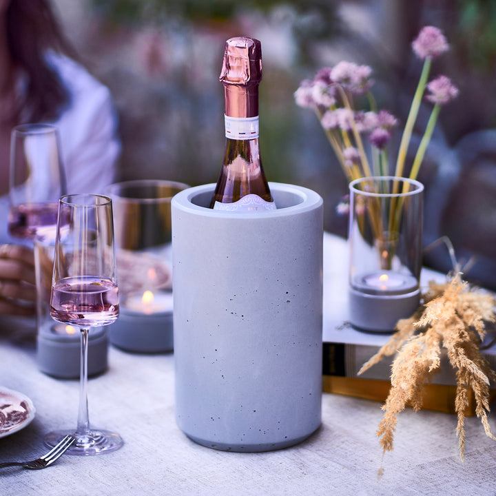 weinkühler und sommerdeko mit blumen auf einem Gartentisch mit Weinflasche in Flaschenkühler aus Beton